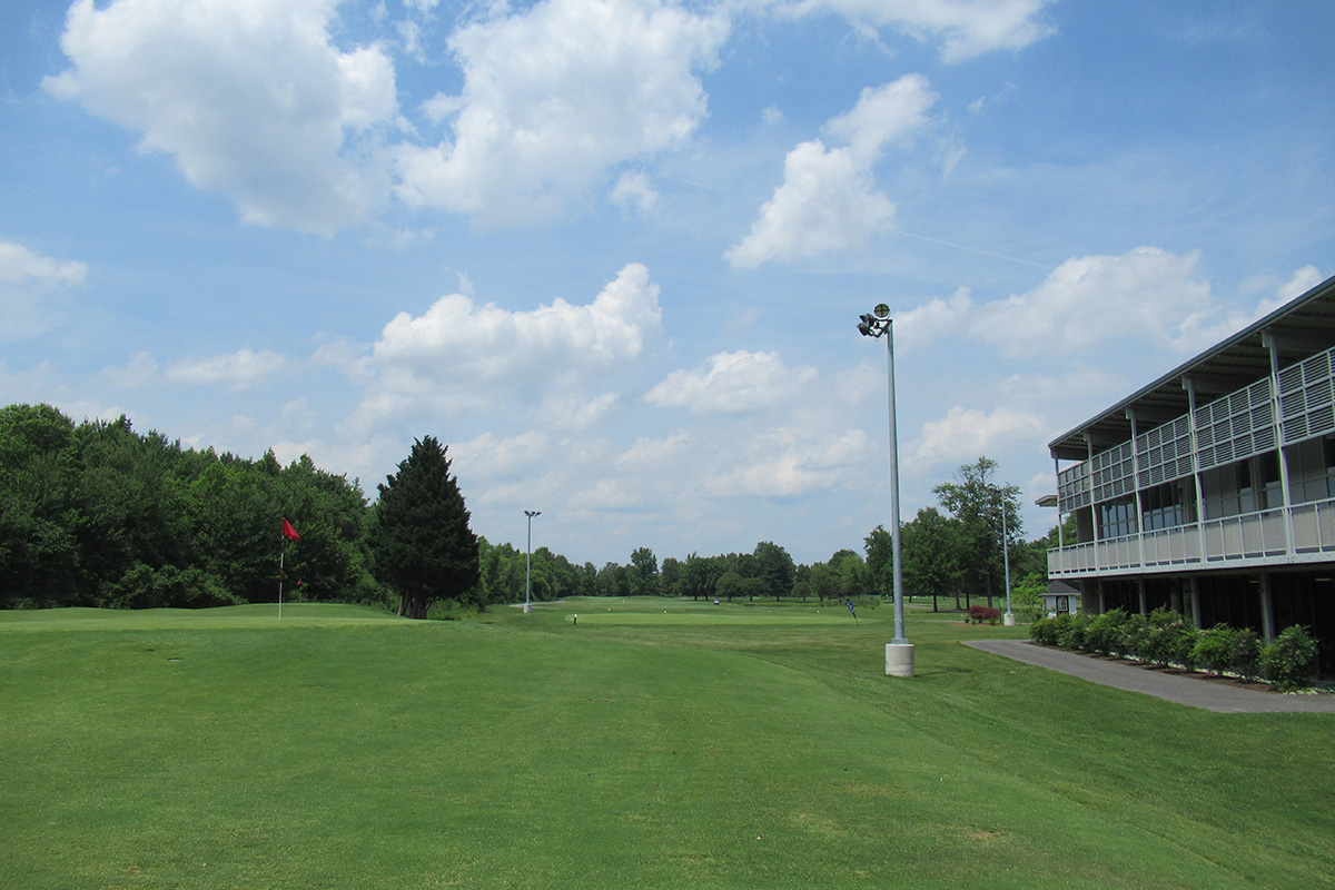 A multi-story building with a long balcony overlooking a hole on a golf course.
