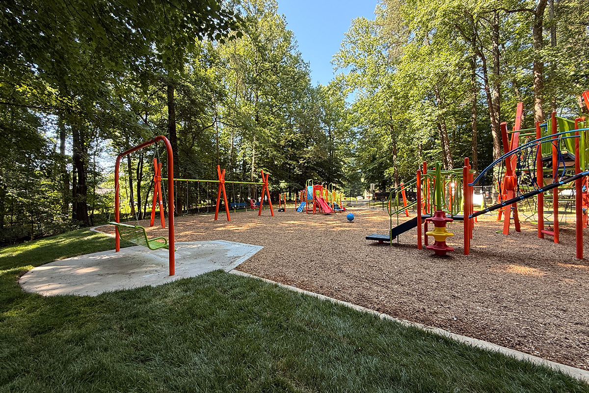 Inclusive sway bench featuring a high-back swinging bench, traditional swings, and play structures connected by accessible routes.