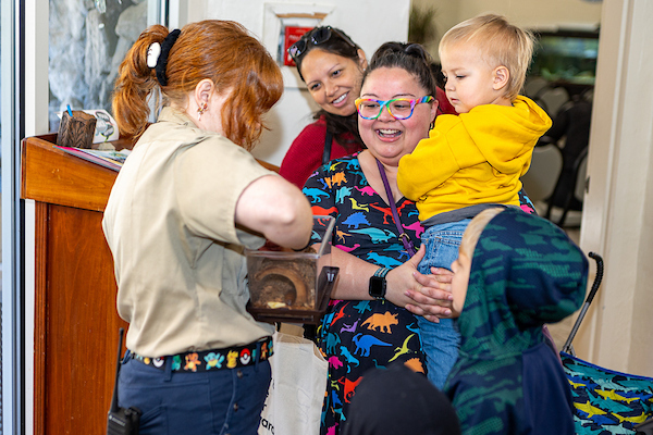 A ranger holds a small plastic animal enclosure up so visitors can see inside.