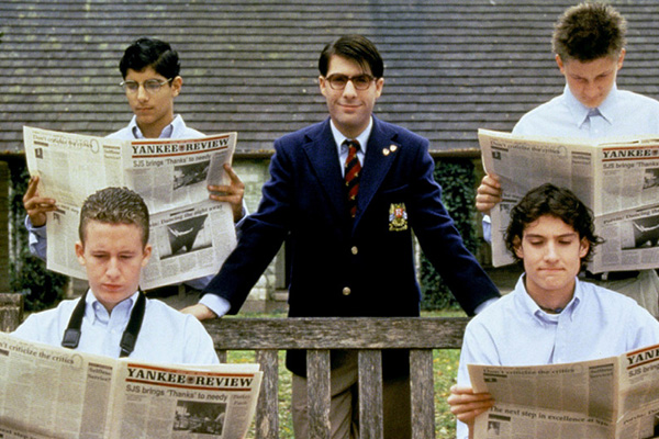 Publicity still from the film Rushmore depicting the main character in a school blazer surrounded by classmates reading a newspaper called Yankee Review.